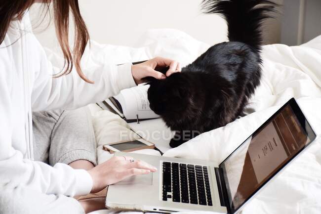 Ragazza adolescente seduta a letto con il suo cane utilizzando il suo computer portatile — Foto stock