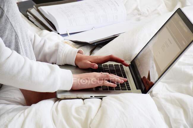 Дівчина-підліток сидить у ліжку, використовуючи свій ноутбук — стокове фото