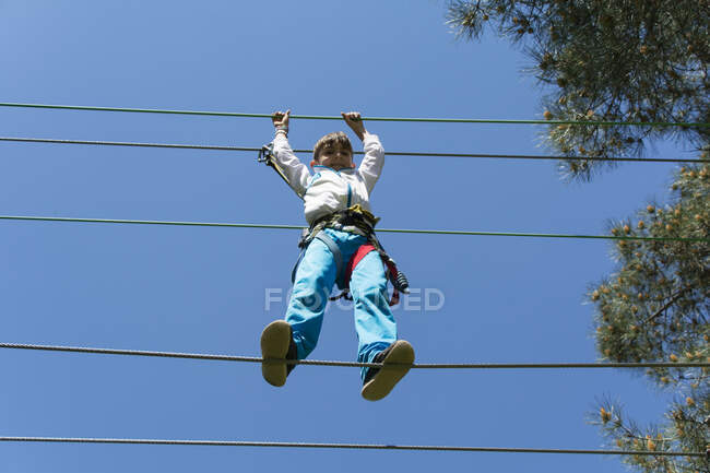 Boy in a harness tightrope walking — Stock Photo