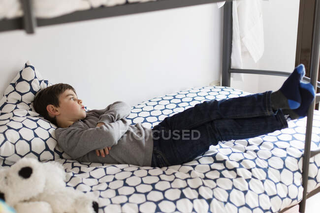 Junge liegt tagträumend auf seinem Bett — Stockfoto