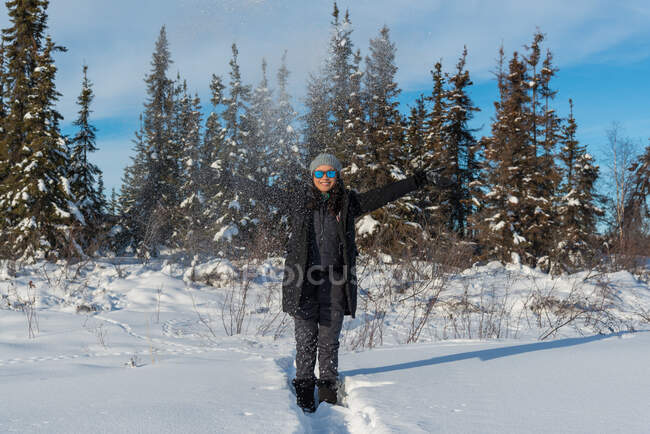 Femme souriante avec les bras tendus debout dans la neige, Yellowknife, Territoires du Nord-Ouest, Canada — Photo de stock