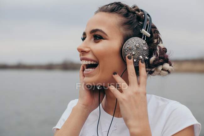 Retrato de una mujer sonriente con auriculares con pinchos - foto de stock