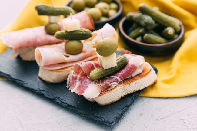 Bruschetta with prosciutto, olives, cheese and gherkins — Stock Photo