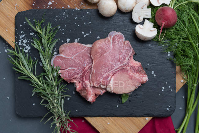 Raw veal with rosemary and mushrooms on table — Stock Photo