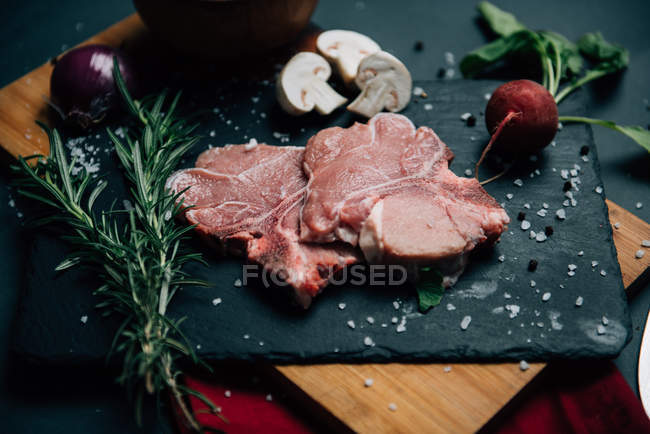 Veal with rosemary and mushrooms over black slab — Stock Photo