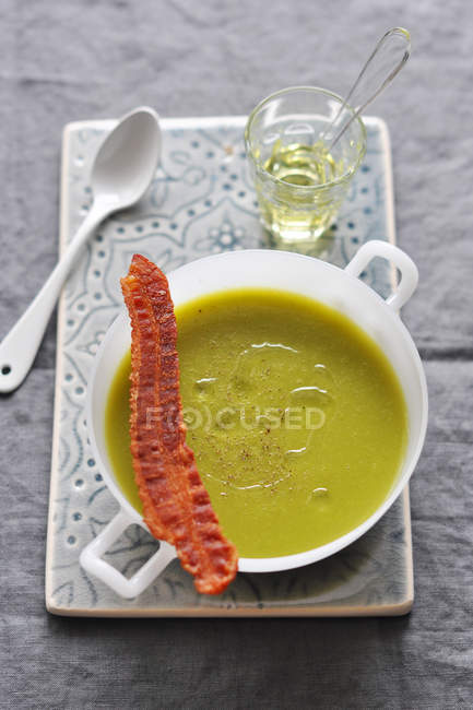 Pea soup with bacon and olive oil over table — Stock Photo