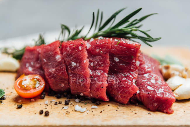 Steak with tomatoes, garlic and herbs on chopping board — Stock Photo