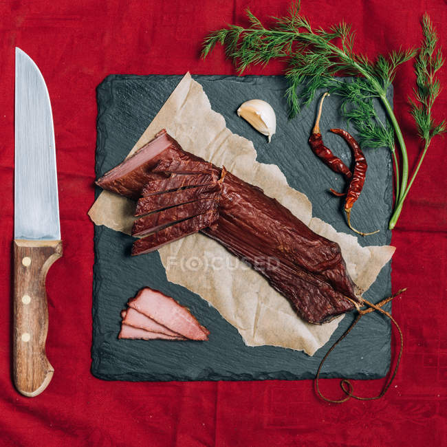 Cured ham with garlic, chili and dill garnish — Stock Photo