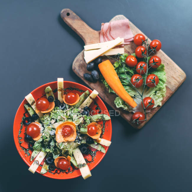 Salad and chopping board with fresh vegetables — Stock Photo