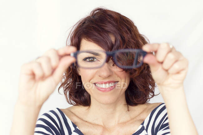 Mulher sorridente segurando um par de óculos — Fotografia de Stock