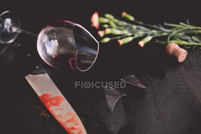 Zerbrochenes Weinglas, Blumen und ein blutiges Messer — Stockfoto