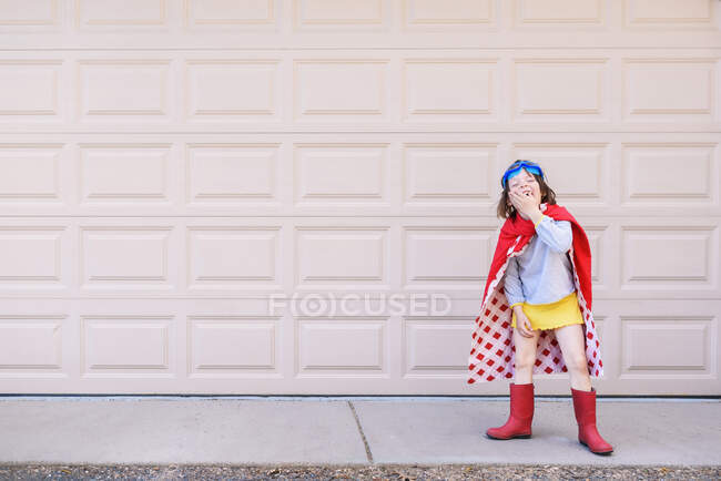 Menina vestida como um super-herói na frente da porta da garagem — Fotografia de Stock