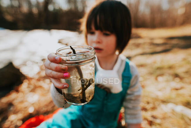 Chica sosteniendo un frasco con insectos de agua - foto de stock