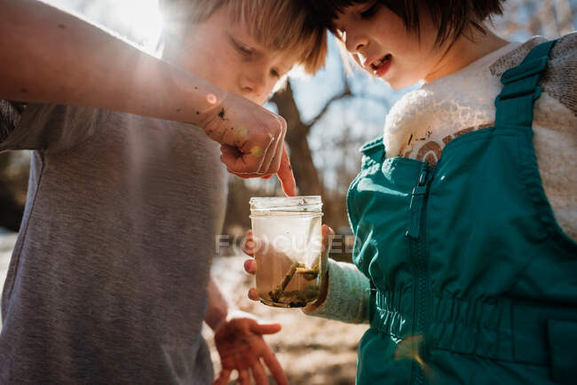 Menino e menina segurando um frasco com insetos da água — Fotografia de Stock