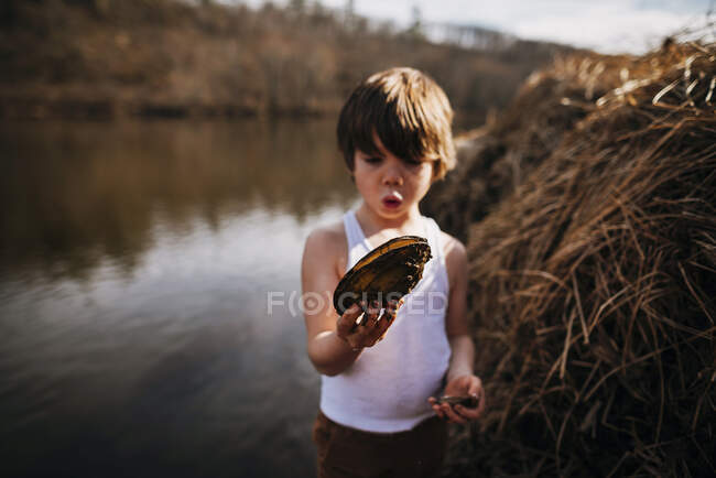 Junge am Strand hält Muschel in der Natur — Stockfoto