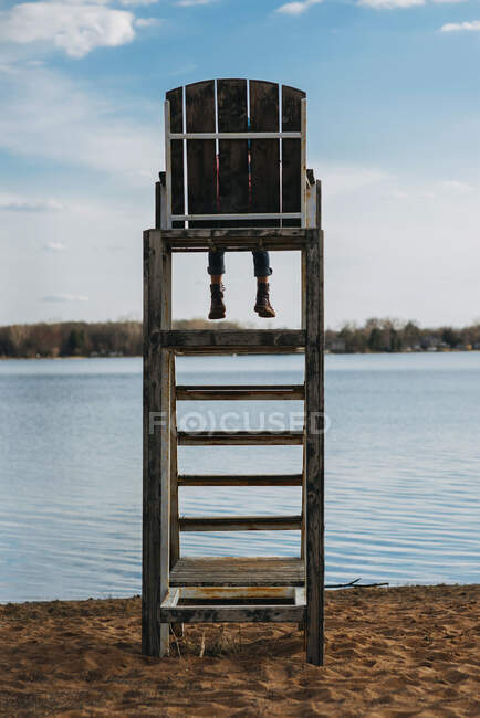 Girl sitting on lifeguard chair overlooking lake — Stock Photo