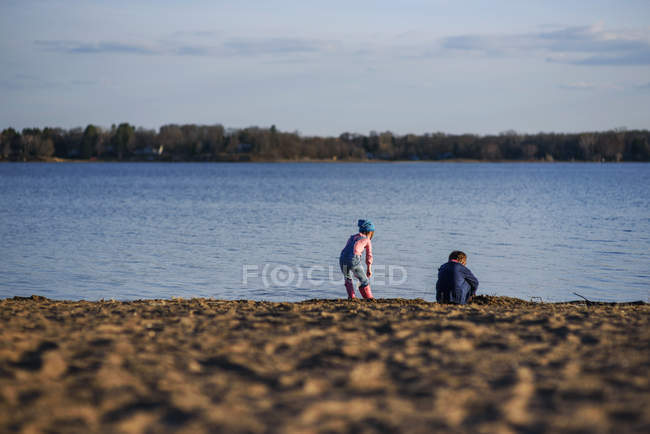 Ragazzo e ragazza che giocano sul bordo di un lago — Foto stock