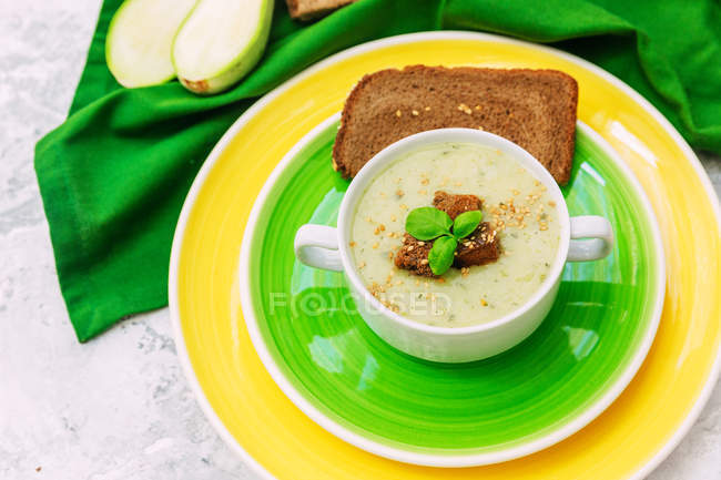 Zucchini soup with rye bread over colorful plates — Stock Photo