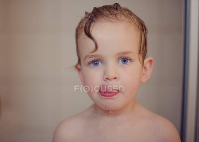 Retrato de um menino no chuveiro lambendo os lábios — Fotografia de Stock