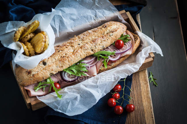 Ham sandwich and potato fries wrapped in paper — Stock Photo