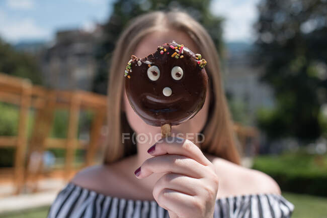 Женщина, держащая счастливое лицо мороженое перед лицом — стоковое фото