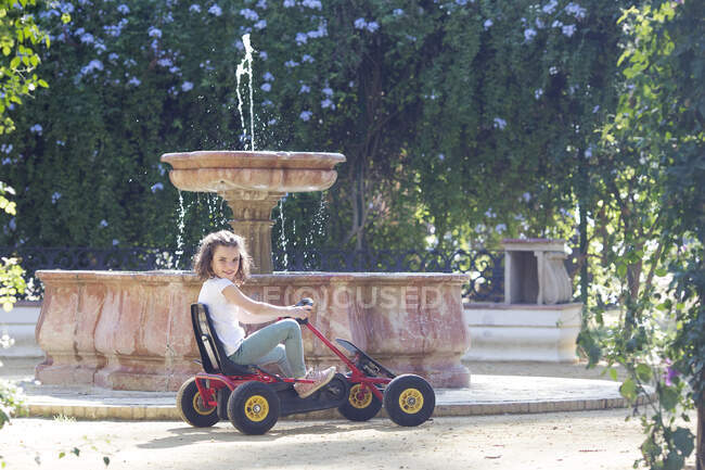 Девушка за рулем на повозке в парке в солнечный день — стоковое фото