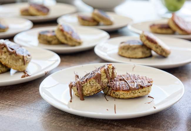 Crêpes à la banane avec tartinade au chocolat sur assiettes blanches, table servie — Photo de stock