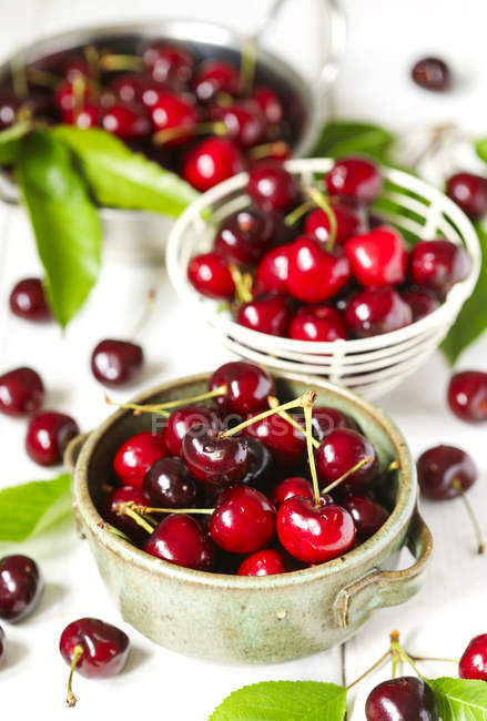 Sweet red cherries in transparent bowls over white table — Stock Photo