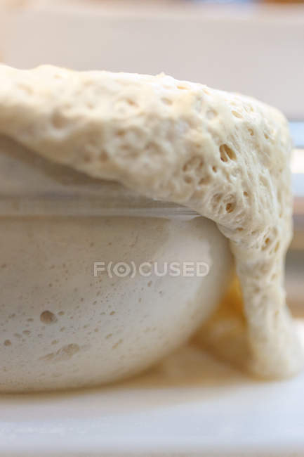 Pâte se levant sur le bord d'un bol en verre — Photo de stock