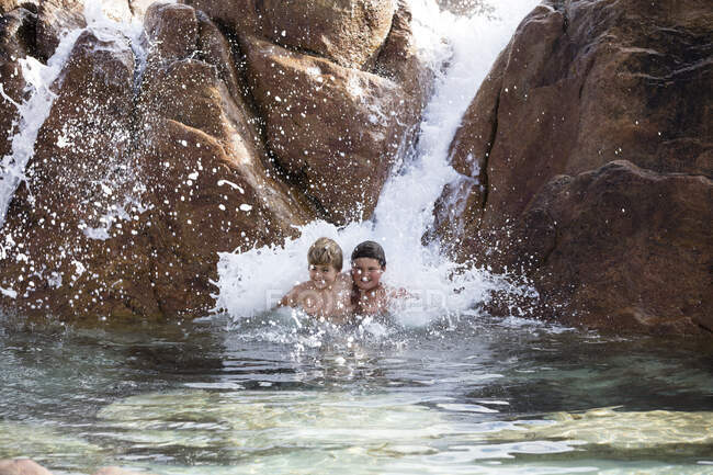 Zwei Jungen spielen in einem Wasserfall, Westaustralien, Australien — Stockfoto