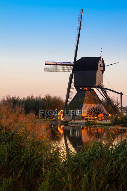 Moinho de vento sobre o canal de água ao pôr do sol, Kinderdijk, Países Baixos — Fotografia de Stock