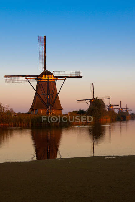 Windmills over water channel at sunset, Kinderdijk, Netherlands — Stock Photo