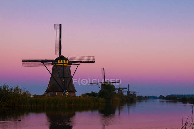 Windmills over water channel at sunset, Kinderdijk, Netherlands — Stock Photo