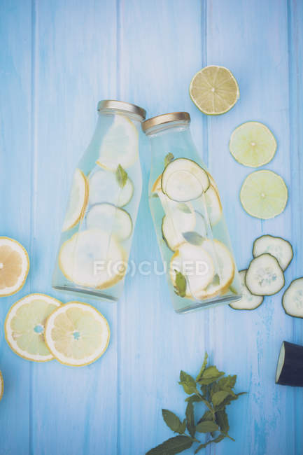 Две бутылки воды с огурцом, лимоном, лаймом и мятой — стоковое фото
