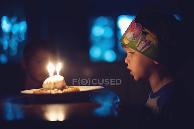 Мальчик задувает свечи на торте на день рождения — стоковое фото