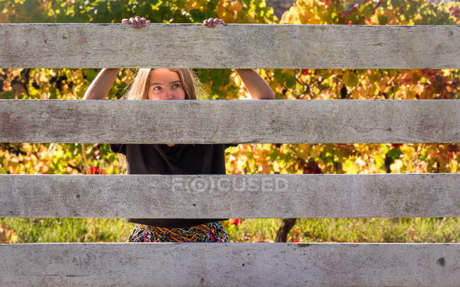 Fille se cachant derrière une clôture — Photo de stock