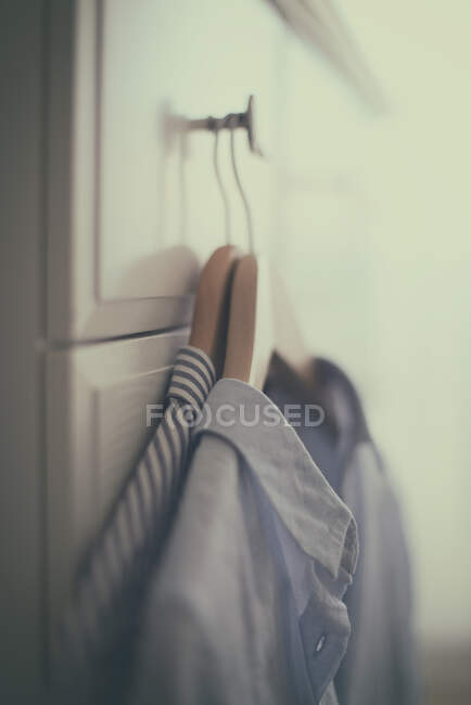 Two shirts on coat hangers hanging on a wardrobe — Stock Photo