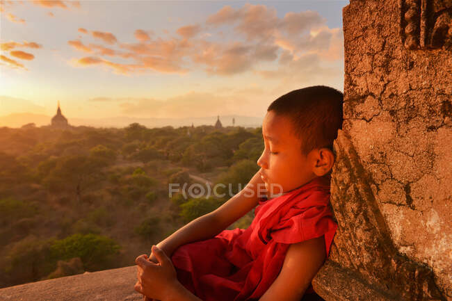 Monje relajarse en el antiguo templo durante la puesta del sol, Bagan Myanmar - foto de stock