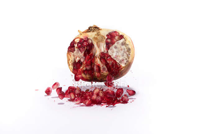 Pomegranate seeds with leaves isolated on white — Stock Photo