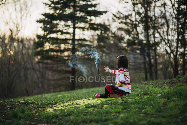 Girl sitting outside holding a smoking stick — Stock Photo