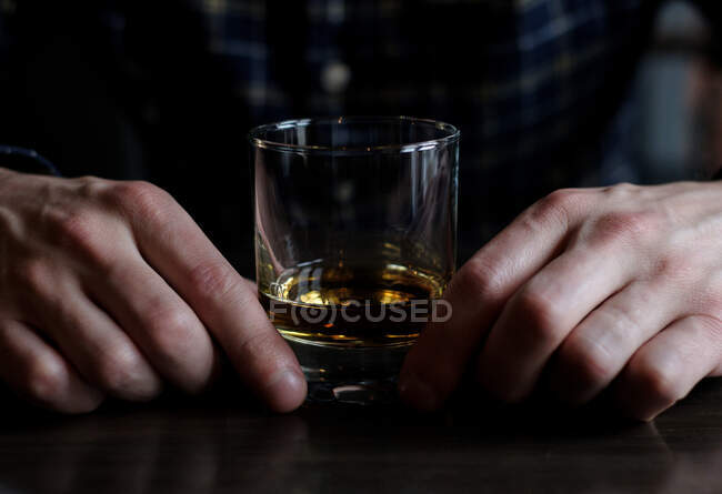 Hombre sentado en un bar con un vaso de whisky - foto de stock