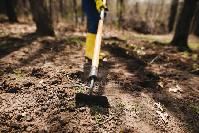 Garçon creuser la terre avec une houe — Photo de stock