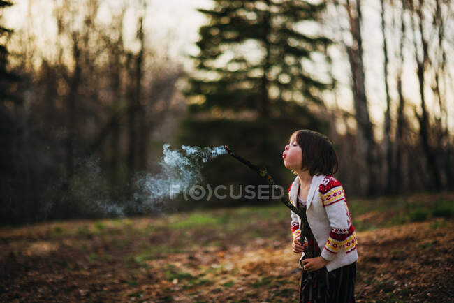 Девушка, дующая палкой на природу — стоковое фото