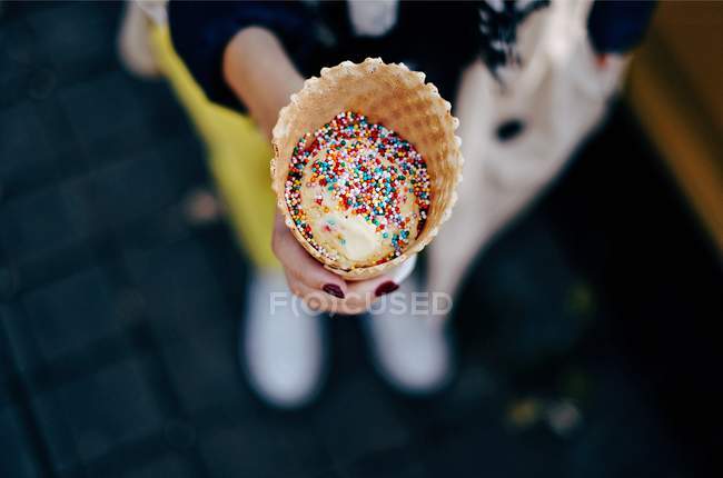 Woman holding an ice-cream with sprinkles — Stock Photo