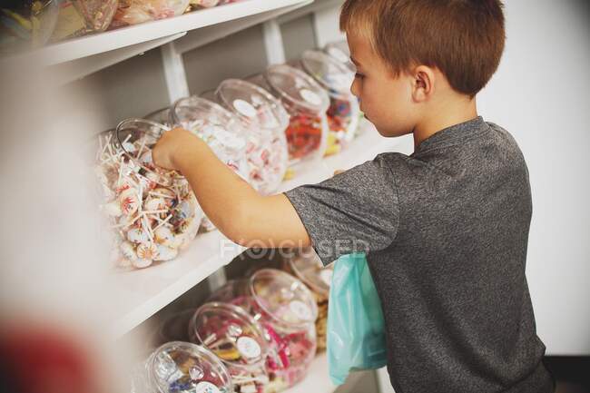 Мальчик собирает сладости в кондитерской — стоковое фото