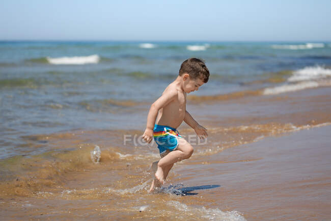 Мальчик на пляже выбегает из моря, Корфу, Греция — стоковое фото