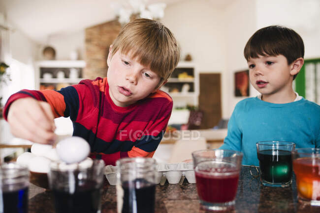 Два мальчика, стоящие на кухне и умирающие пасхальные яйца — стоковое фото