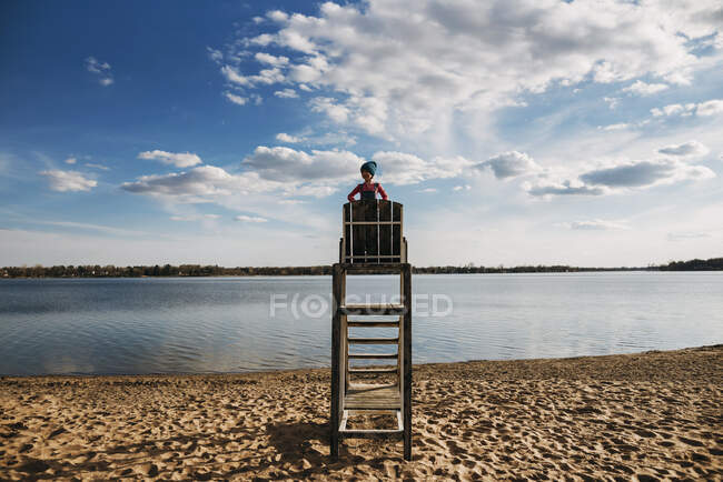 Mädchen steht auf einem Bademeisterstuhl am See — Stockfoto