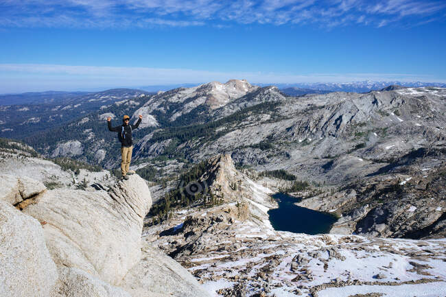 Man standing on Alta Peak with arms raised, Pear lake and Giant Sequoia forest in the distance, California, America, USA — Stock Photo