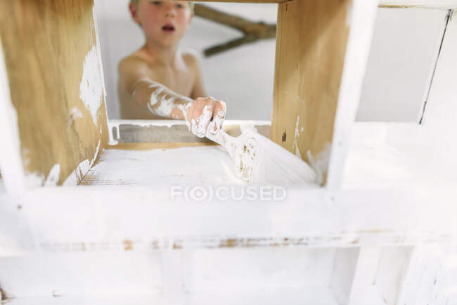 Boy painting a wooden chicken coop — Stock Photo